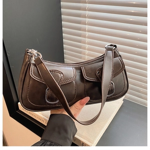 Detailed view of dark brown vintage baguette bag with dual pockets and silver buckles