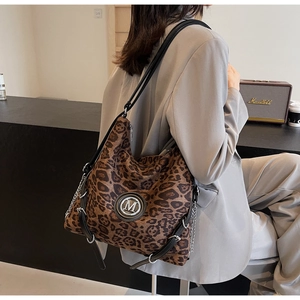 Detail der Vintage-Leoparden-Tragetasche mit silbernem M-Logo und schwarzem Lederriemen
