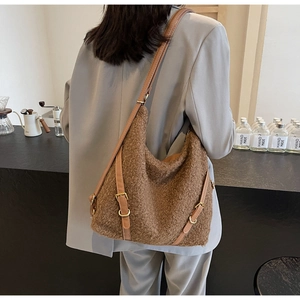 Detailansicht der braunen Plüsch-Tasche mit Lederriemen und Metallschnallen an einem Model