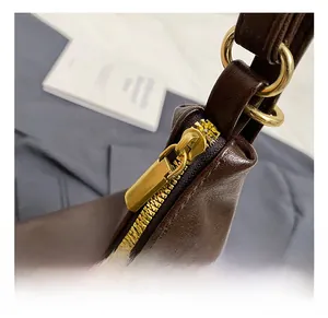 Close-up of vintage brown leather tote featuring gold metal zipper and circular hardware