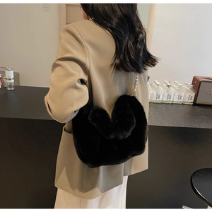 Detail of a black faux mink fur heart-shaped bag with a golden metal chain strap