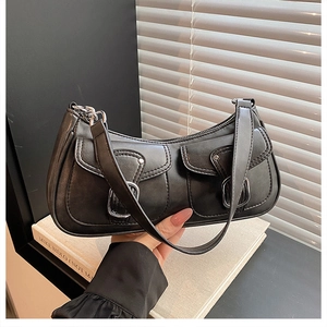 Detail of black matte leather underarm bag featuring two front flap pockets with silver buckles