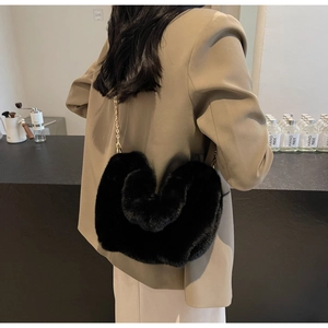 Detail of black faux fur shoulder bag with elegant golden chain strap shown in a cafe