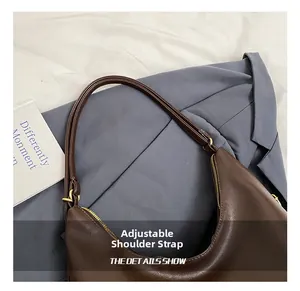 Detail of adjustable shoulder strap with golden buckles on a brown hobo tote bag