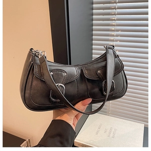Close-up of black leather underarm bag featuring dual pockets and silver metal buckles