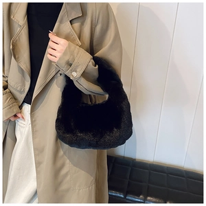 Detail of black faux fur dumpling bag held by model wearing a khaki trench coat