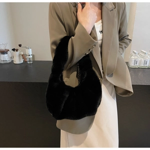 Detail of a chic black faux fur hobo bag with a metal chain strap on a model
