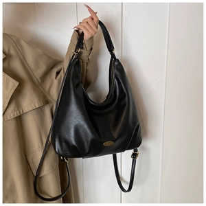 Close-up of black lychee texture hobo bag with gold metal plaque and zipper detail