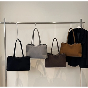 Four colors of minimalist suede tote bags hanging on a display rack for autumn style