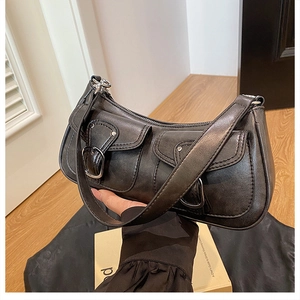 Detail of a black vintage leather underarm bag featuring silver buckles and double pockets