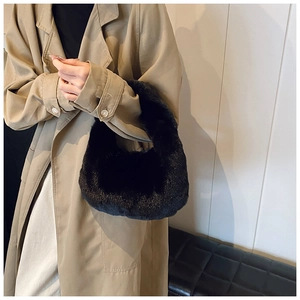 Close-up of black faux fur dumpling bag styled with a beige trench coat for autumn fashion