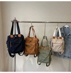 Multiple stylish nylon backpacks in blue, brown, green, and white hanging on a rack