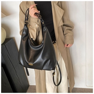 Detail of matte black tote bag showing gold zipper and leather texture in a soft light