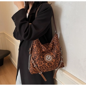 Detail der Leopard-Tragetasche mit metallischem M-Logo und Kettenriemen-Dekoration