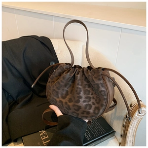 Detailaufnahme der Leoparden-Beuteltasche auf beigem Sofa mit Mode-Requisiten