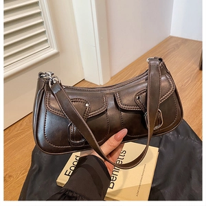 Detail of a dark brown retro shoulder bag with dual buckled pockets and textured faux leather