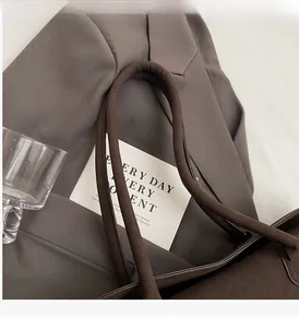 Detailed close-up of dark brown suede tote bag handles with professional sewing