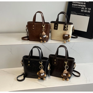 Mini sacs cabas en quatre couleurs sur escalier en marbre avec porte-clés peluche