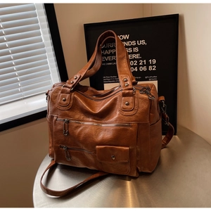 Détail d'un sac de voyage vintage en cuir PU marron avec plusieurs poches zippées et clous