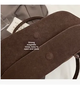 Detail view of strong magnetic closure and stitching on brown suede leather tote bag