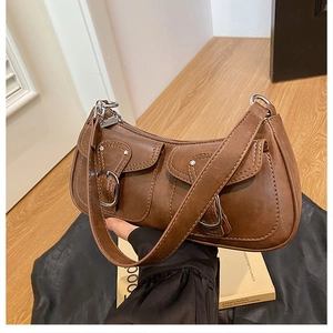 Close-up of brown vintage baguette bag featuring two front pockets and silver buckles