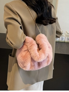 Pink faux fur crossbody bag with gold chain strap shown on model in stylish setting