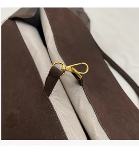 Detail of premium gold-tone metal hook and textured herringbone lining on a suede bag