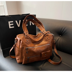 Détail du sac de voyage en cuir PU marron avec fermetures éclair et texture vintage