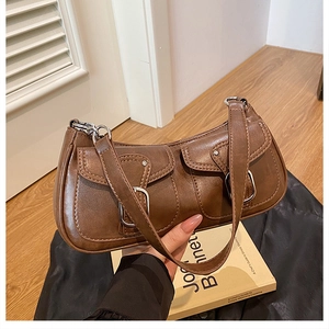 Close-up of retro brown shoulder bag featuring dual front pockets and silver buckles