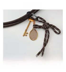 Detailed close-up of woven rope keychain with metal key and tennis racket pendant