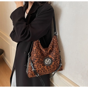 Detail der Hobo-Tasche mit Leopardenmuster, silbernem M-Logo und Metallkette am Mantel