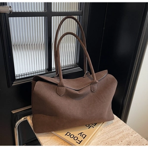 Macro detail of dark brown faux suede texture and long shoulder straps on a tote bag