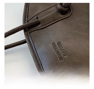 Detailed macro view of dark brown leather texture with embossed lettering and cord detail