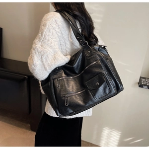 Gros plan d'un grand sac bandoulière vintage en cuir noir avec plusieurs poches zippées