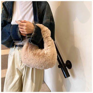 Detailed texture of khaki plush dumpling bag held by model wearing a denim jacket