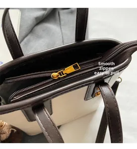 Gros plan d'une fermeture éclair dorée fluide sur un sac seau bicolore texturé