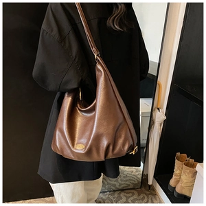 Close-up of the vintage brown leather tote bag texture and elegant metal logo detail