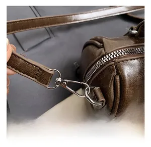 Detailed macro view of dark brown leather Boston bag with metallic hooks and zipper
