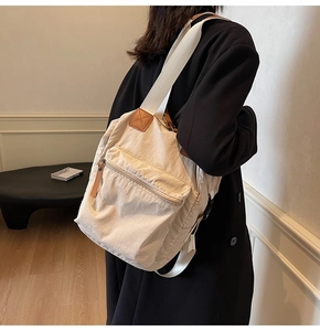 Side view of cream nylon backpack featuring leather trim and canvas straps on model