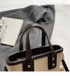 Détail du sac cabas crème avec poignées en cuir marron robustes et rivets dorés polis