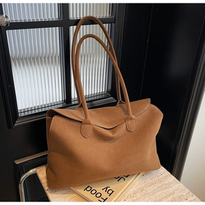 Detailed macro view showing the grainy texture and caramel suede material of the tote bag
