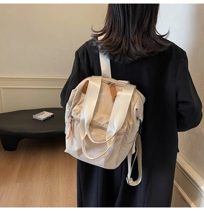 Detailed view of beige waterproof nylon backpack with multiple zipper pockets on model