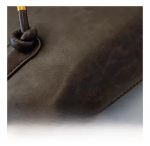 Detail view of dark brown matte leather material with golden hardware and knotted strap