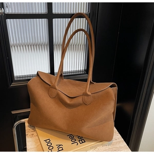 Close-up of brown suede tote bag with long handles on a stone countertop