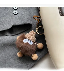 Détail d'un charm monstre en peluche marron avec bonnet sur un sac à main en cuir beige