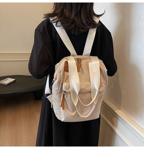 Rear view of cream nylon backpack on model showing minimalist style and compact fit