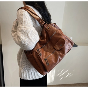 Détail d'un grand sac de voyage vintage en cuir PU marron avec plusieurs poches zippées