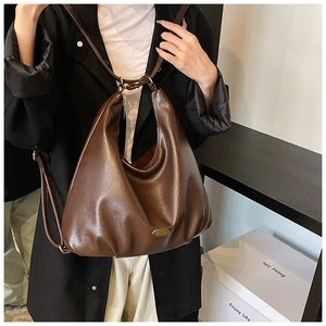 Detail of dark brown faux leather hobo bag with adjustable strap and metal logo