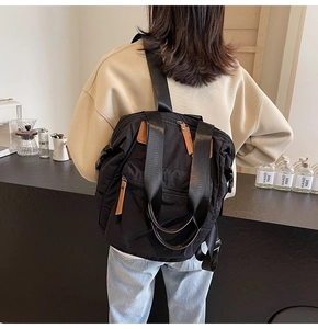 Close-up of a large black nylon backpack with brown leather accents on model