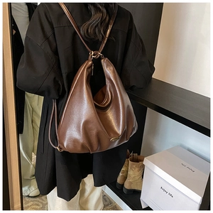 Brown faux leather tote bag showing side view on a model in a minimalist room